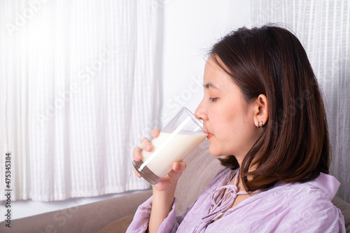 Young pregnant woman drinking milk sitting on sofa in the living room. healthy food eating for life.