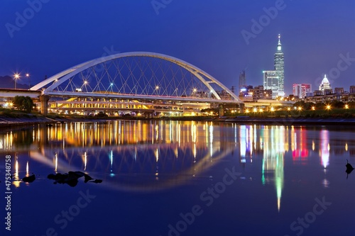 Night scenery of Taipei City with beautiful reflections of skyscrapers & bridges on the water by riverside at dusk ~ Cityscape of Taipei 101 Tower, Keelung River, Xinyi District & downtown in twilight