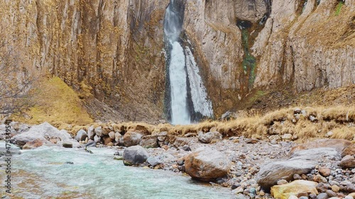 A large waterfall in a beautiful rocky gorge with a river photo