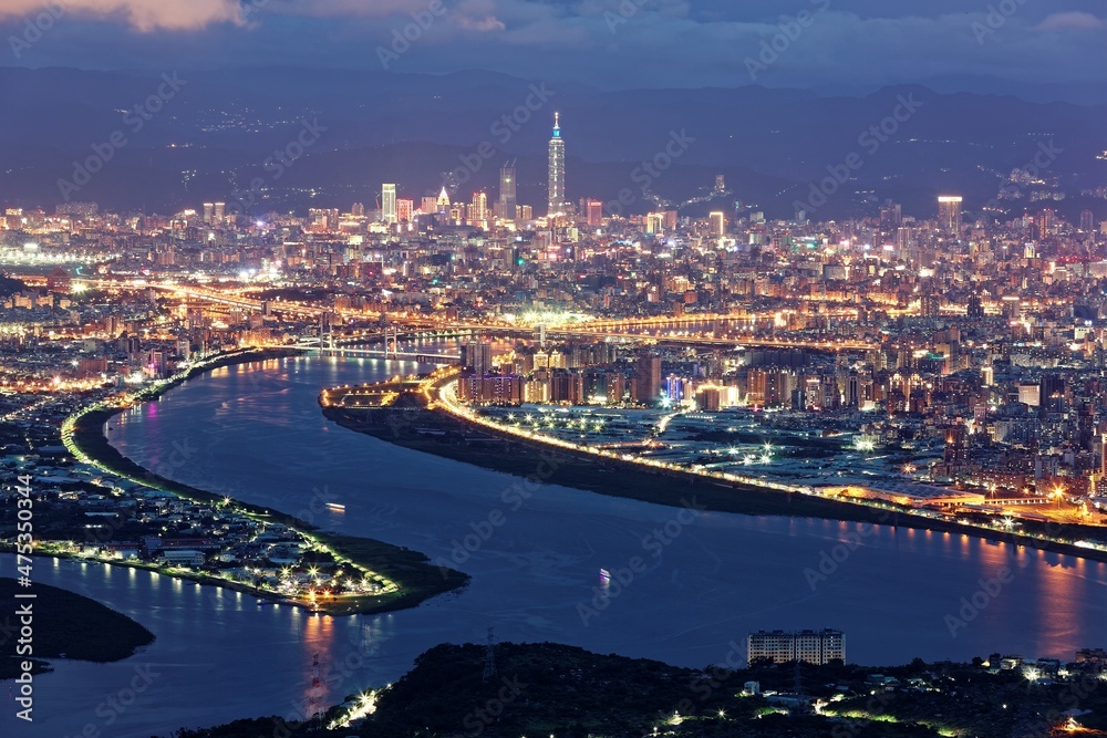 Fototapeta premium Aerial panorama over Taipei, the capital City of Taiwan, on a blue gloomy evening with view of the confluence of Tamsui & Keelung River & Taipei 101 Tower amid highrise skyscrapers in Downtown at dusk