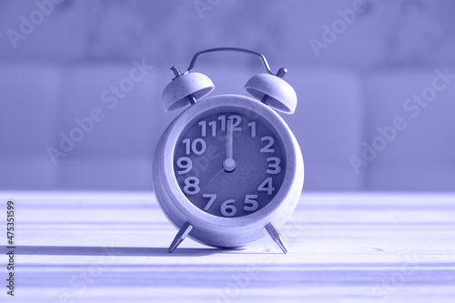 Close up clock for decoration at 8 o'clock stands on a wooden texture with copy space. Very peri toned image. Copy space