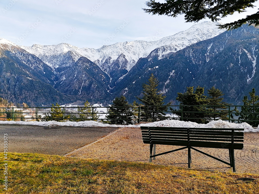 Panchina nel bosco con vista panoramica sulle cime delle Alpi innevate a Sondalo, in Valtellina. Italia