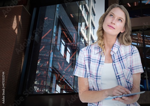 Composite image of caucasian woman using digital tablet against tall buildings photo