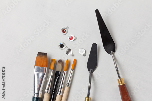 Fototapeta Naklejka Na Ścianę i Meble -  Foil caps from tubes of paint and a set of art brushes and palette knives