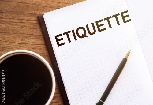 The inscription in the notepad ETIQUETTE, next to glasses, a pencil and a cup of coffee on wooden table. A business concept.