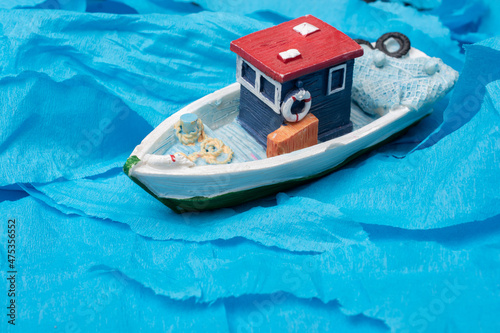 Little colorful model fishing boat on blue