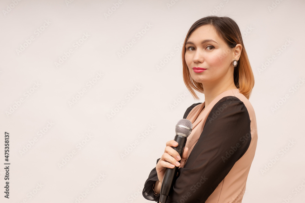 Young woman stands with a microphone in her hands on a white background Young woman stands with a microphone in her hands on a white background