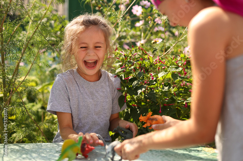 Cute little girls having fun playing with a toy dinosaurs