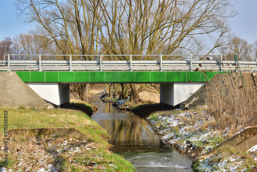 Fototapeta premium A bridge that connects the two banks over a small stream on a cool spring day.