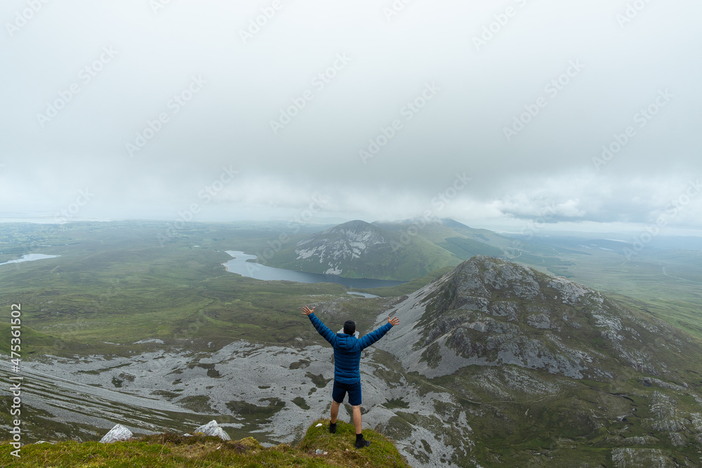 Man standing on top of mountain raising his arms in Errigal mountain