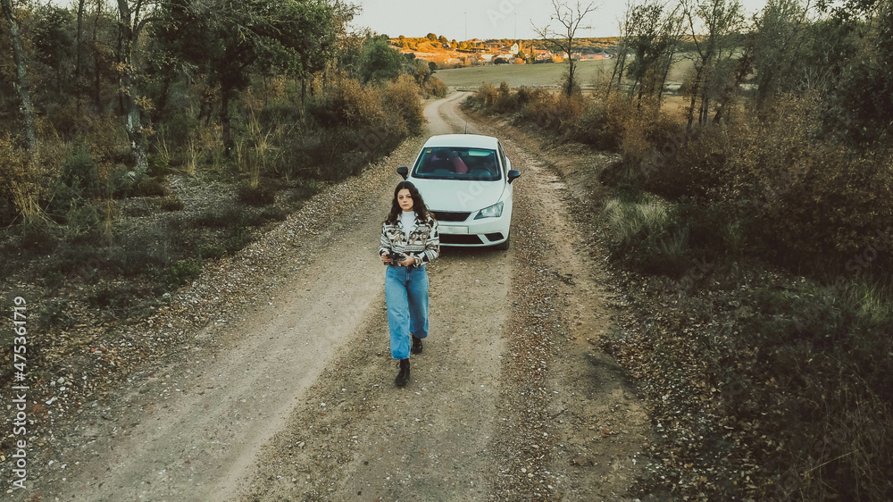 bird's eye view of woman in front of a white car between forest bird's eye view of woman in front of a white car between forest