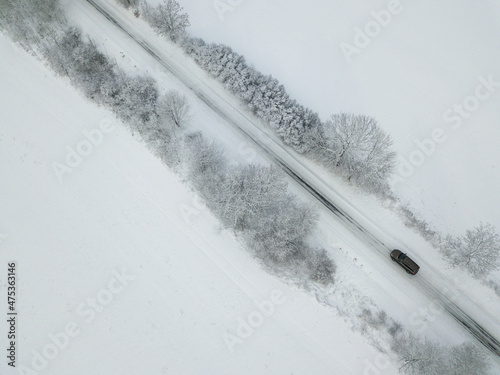 Aerial view of a car on winter road in the forest. Winter landscape countryside.