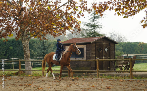 Young boy riding horse at the ranch, learning horseback riding.