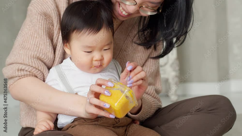 Young Mother Feed Little Baby With Fruit or Vegetable Mash Food. Happy Asian Family Relationship With Lovely Child. Child Eating. Good appetite. Happy Childhood. Young Parent With Baby Boy. Young Mother Feed Little Baby With Fruit or Vegetable Mash Food. Happy Asian Family Relationship With Lovely Child. Child Eating. Good appetite. Happy Childhood. Young Parent With Baby Boy.