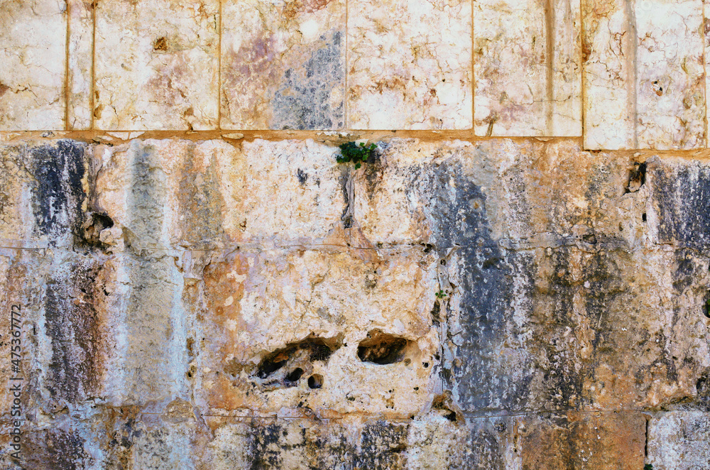 Close-up view of yellow ancient wall. Old wall of large light blocks of marble tiles. Wall with interesting structure. Outdoor and indoor interiors. Grunge texture background Close-up view of yellow ancient wall. Old wall of large light blocks of marble tiles. Wall with interesting structure. Outdoor and indoor interiors. Grunge texture background