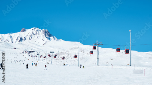 Chairlift on the snow covered ski slope. Bright winter sunny day at ski resort. Erciyes mount, Kayseri, Turkey photo