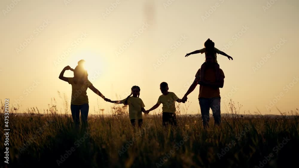 Happy family concept. Dad mom and children walk at sunset in the park. Active lifestyle concept. Parents with children holding hands at sunset. Happy family having fun in park. Silhouette of family