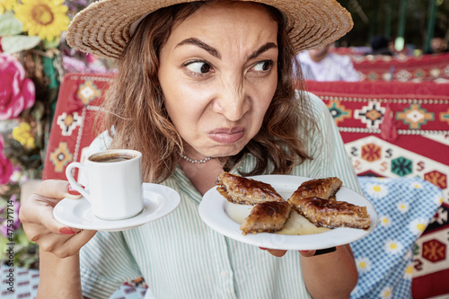 A woman sniffs dessert in a cafe with disgust on her face. The concept of spoiled food and poisoning in catering restaurant