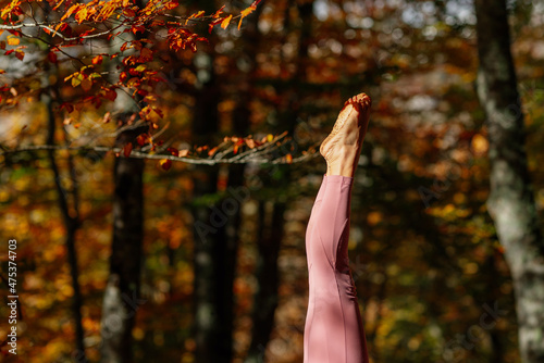 Detail of legs and feet of woman practicing yoga doing balance in the handstand pose in a forest.