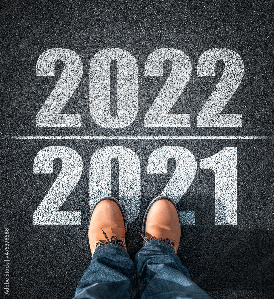 New year 2022, concept. 2022 inscription on the asphalt. The man in boots takes a step into the new year 2022.