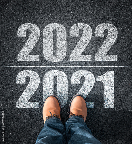 Obraz na płótnie New year 2022, concept. 2022 inscription on the asphalt. The man in boots takes a step into the new year 2022. w salonie