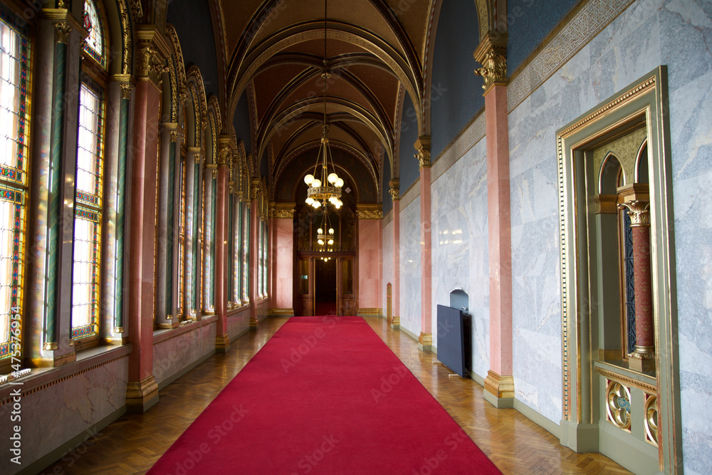 BUDAPEST, HUNGARY - 03 MAR 2019: Long hallway with red carpet on marble floor and chandelier on the ceiling in the Hungarian Parliament building