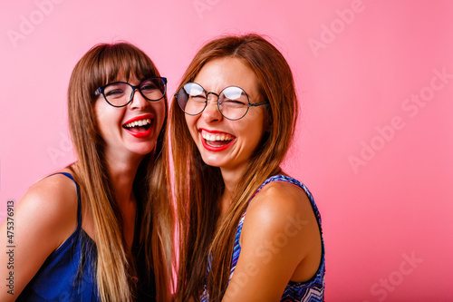 Couple of happy positive beat friends sister girls posing at studio pink background