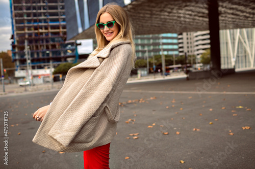 Trendy autumn fashion portrait of stylish young woman posing near modern architecture
