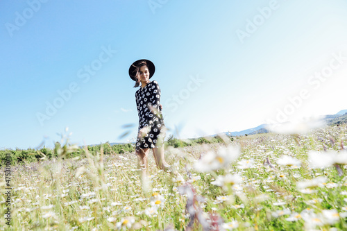 a beautiful woman walks in a field with chamomile flowers © dmitriisimakov