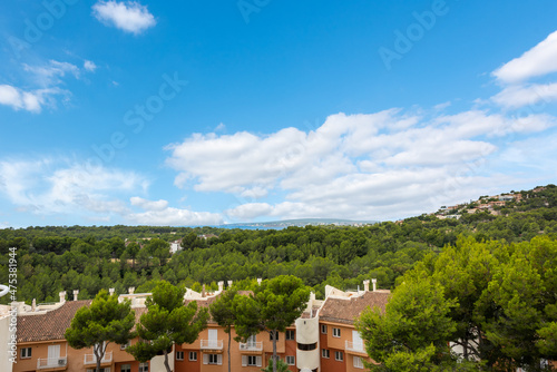 Views from a house with buildings in the foreground surrounded by trees and in the background the Mediterranean Sea  blue sky with white clouds