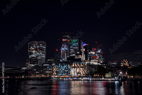 Panoramic view of the London financial district with many skyscrapers in the center of London at night. 