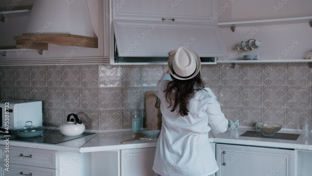 cinematic, happy overweight woman in a hat cooks in the kitchen and dances, good mood, cooking in the evening at home, have fun cinematic, happy overweight woman in a hat cooks in the kitchen and dances, good mood, cooking in the evening at home, have fun