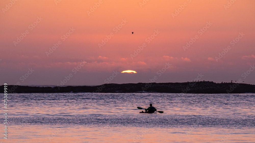 Sunset over Pacific ocean. Silhouette of a man in a canoe watching setting sun at Sunset Bay state Park, Oregon