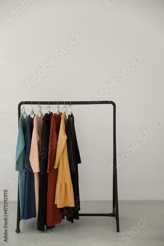 Minimalistic rack with clothes on white studio background.  © Yuliia