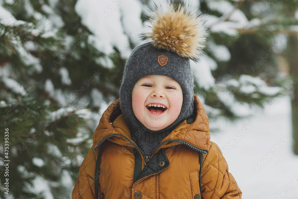 Obraz premium A boy in the winter forest stands and smiles