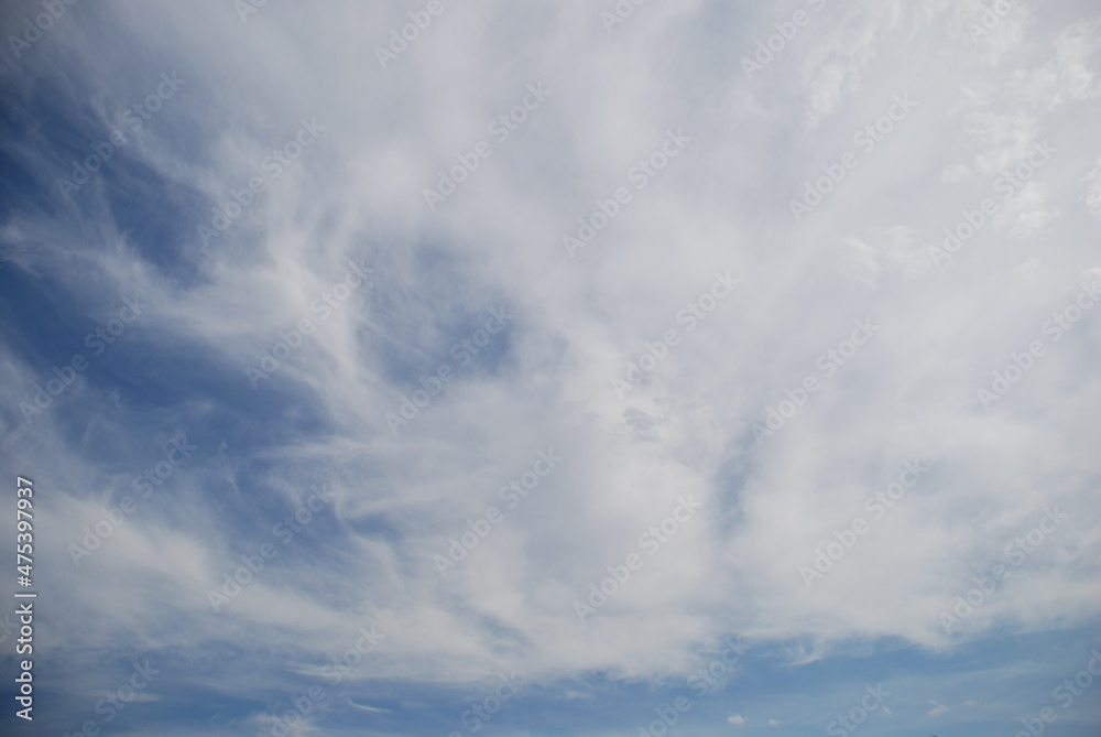 White cirrus clouds over the sky. The light blue sky is flooded with the sun, high white cirrus clouds float across the sky. They stretched out over great distances.