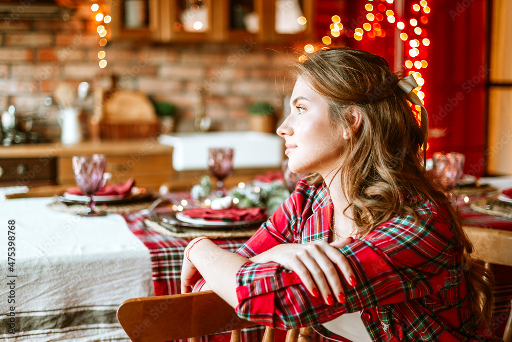 beautiful young woman in red pajamas near decorated Christmas tree in living room for celebration of Christmas and New Year