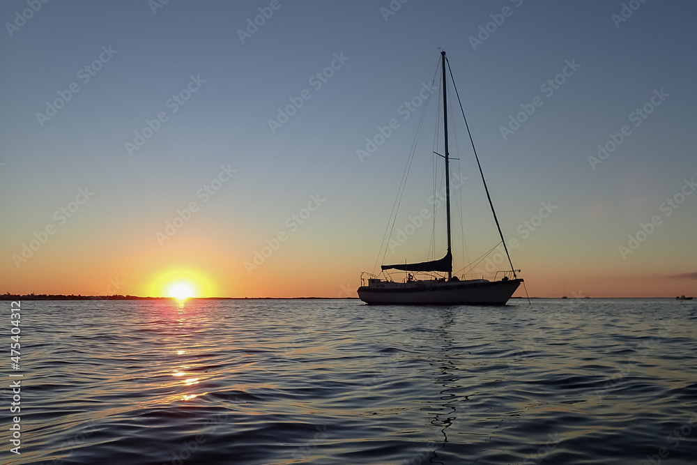 Sailboat silhouettes in the ocean at sunset
