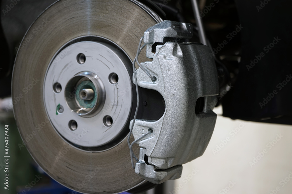 Brake disc and brake caliper installed on a modern car. Selected focus. The background is blurred.