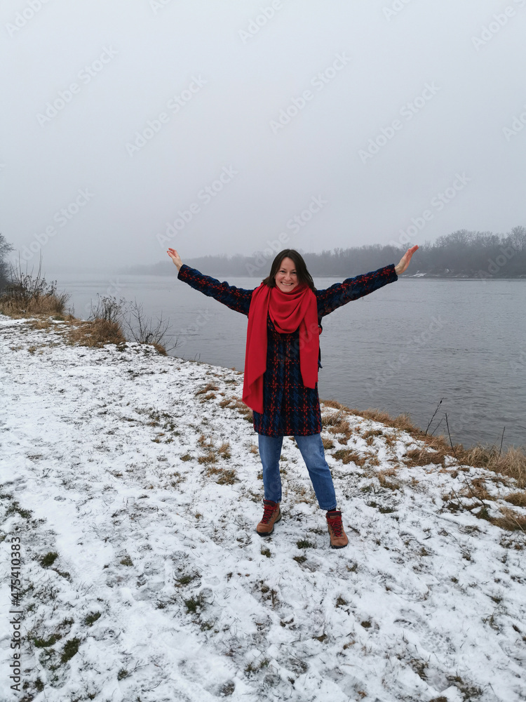 Smiling girl in the winter time on the background of the river and snow
