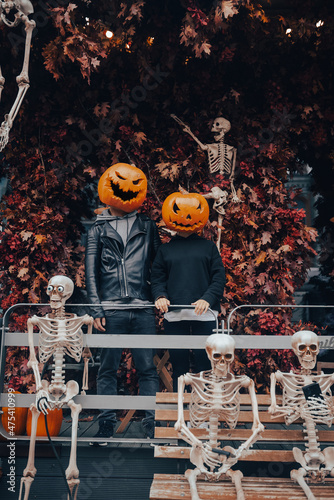 A guy and a girl with a pumpkin heads posing on the street