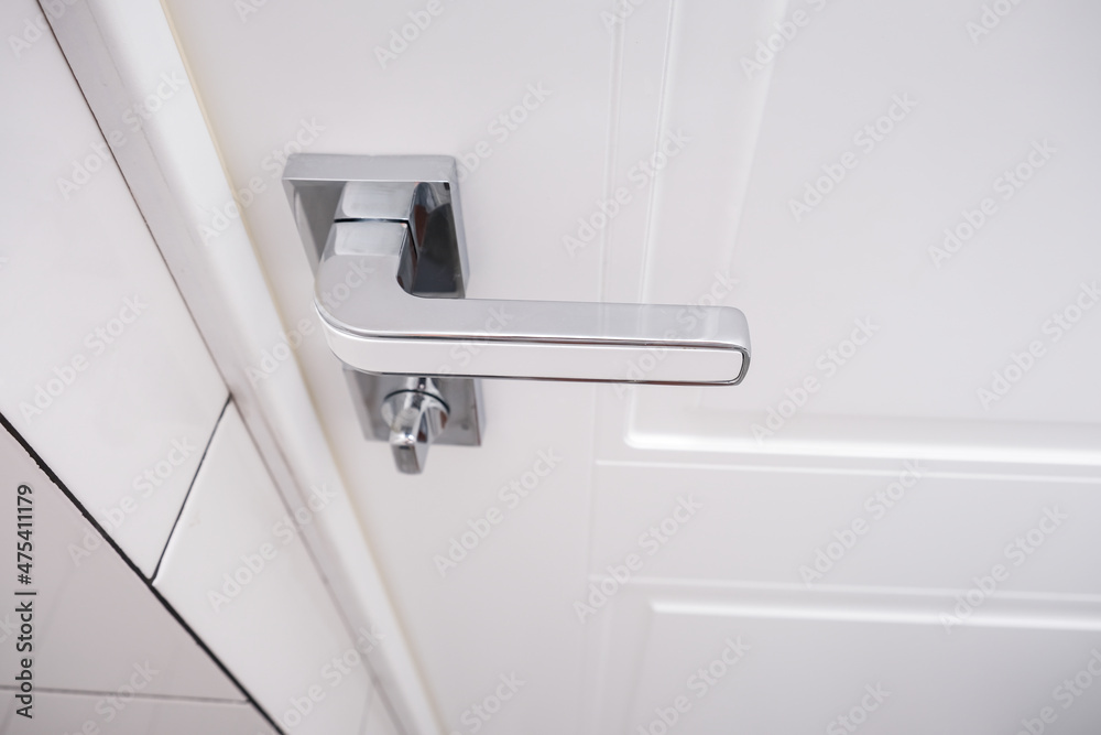 White wooden door with a chrome handle and safety security knob for privacy protection White wooden door with a chrome handle and safety security knob for privacy protection