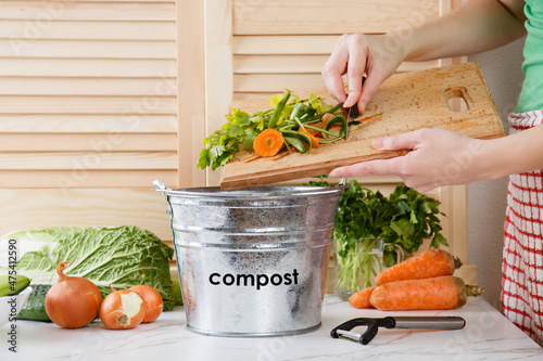 Wonan throws vegetable peeling, scraps in compost bucket. Food waste reduce. Sorting of household waste, composting. Zero waste lifestyle. Collecting of food waste in trash-can for recycling photo