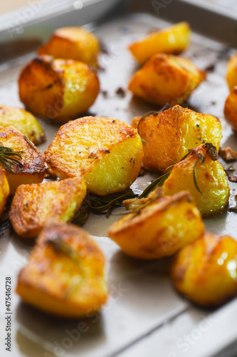 Roasted potatoes on the baking sheet with garlic and rosemary, selective focus