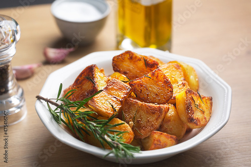 Roasted potatoes in the white plate with garlic and rosemary