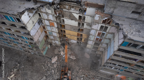 Картината върху платно Excavator for dismantling buildings, using a special claw, dismantles a multi-storey building