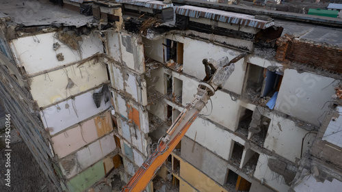 Excavator for dismantling buildings, using a special claw, dismantles a multi-storey building. View from above
