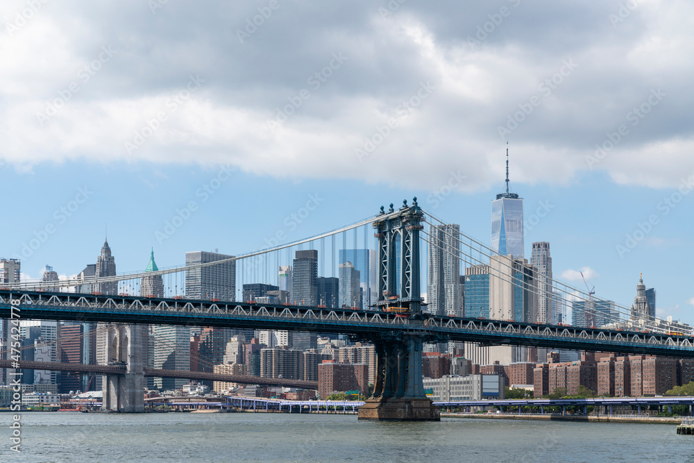 Obraz premium Brooklyn and Manhattan bridge with New York City financial downtown skyline panorama at day time over East River with blue cloudy sky.