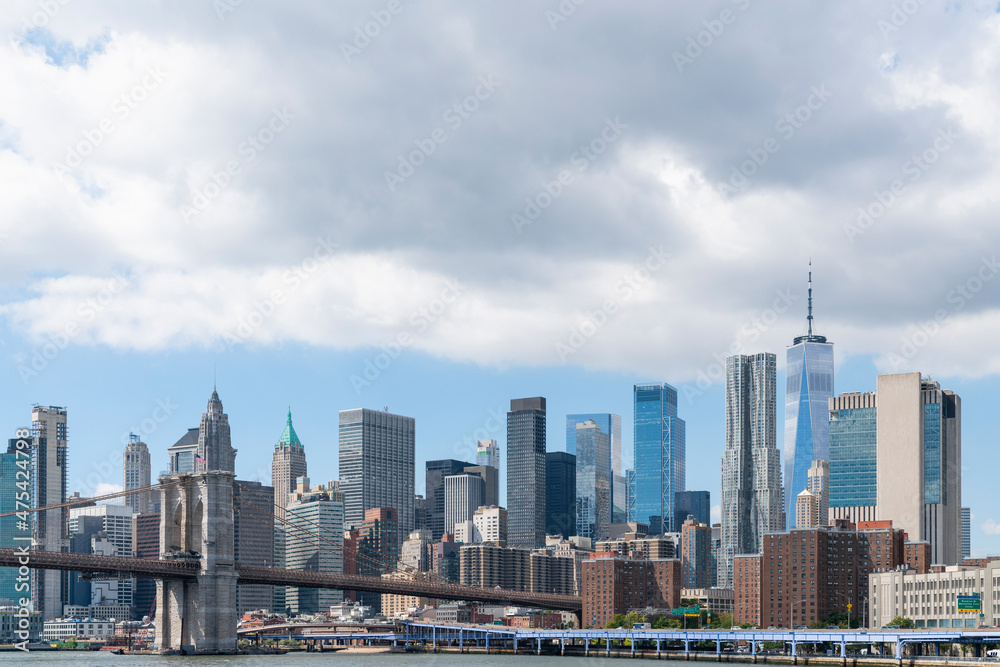 Fototapeta premium Brooklyn bridge with New York City Manhattan financial downtown skyline panorama at day time over East River with blue cloudy sky.