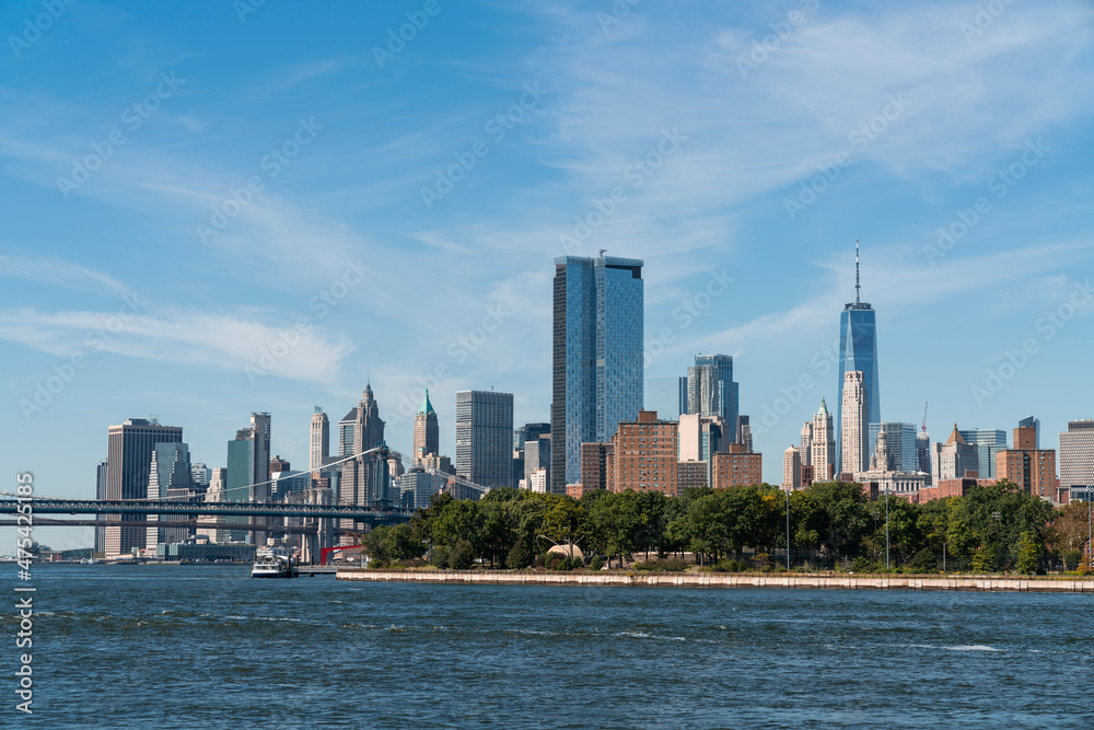 Fototapeta premium Brooklyn and Manhattan bridges with New York City financial downtown skyline panorama at day time over East River with blue cloudy sky.
